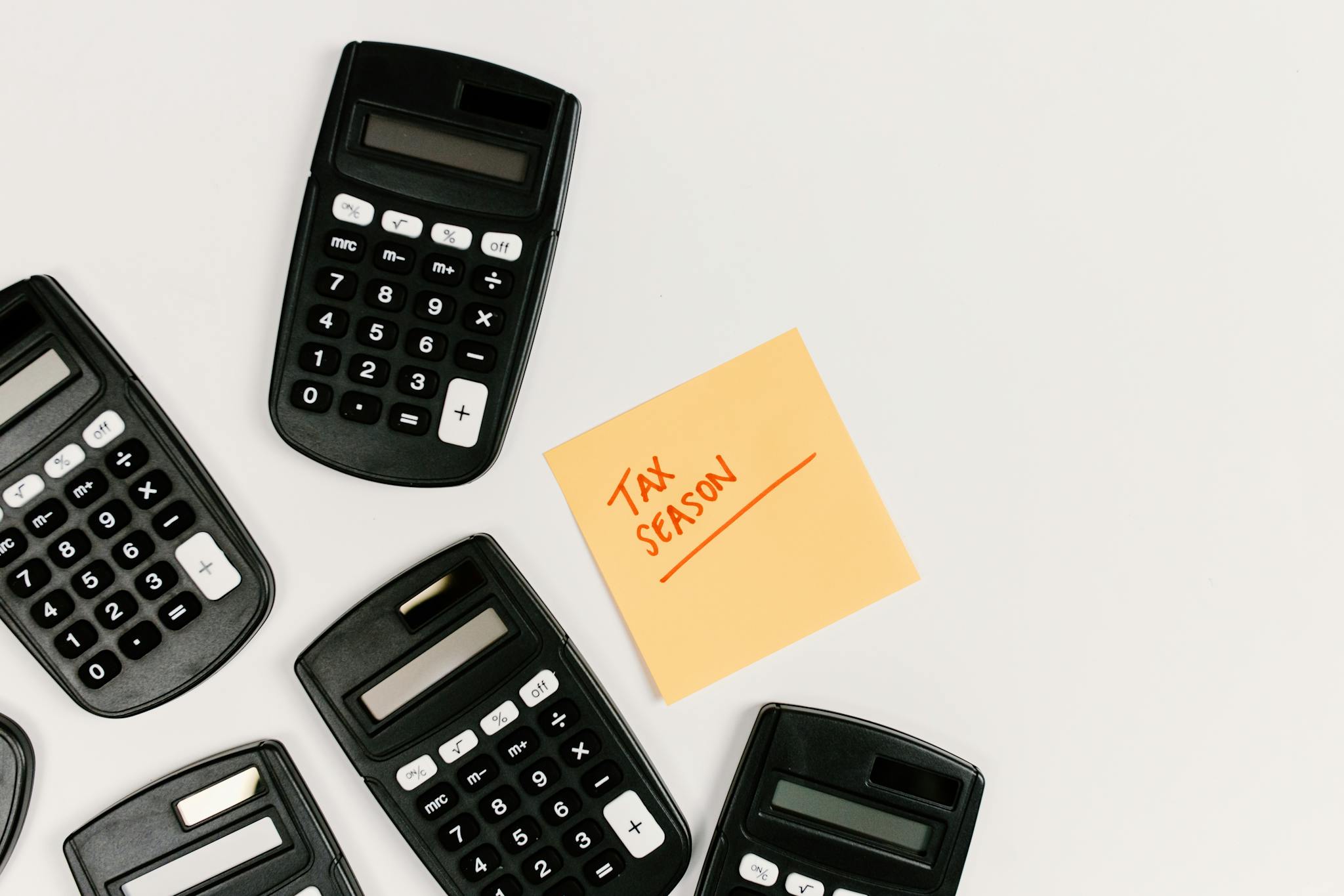 Top view of calculators with a tax season sticky note on a white background.
